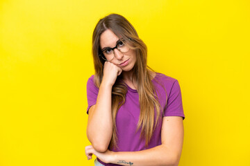 Young caucasian woman isolated on yellow background With glasses and with sad expression