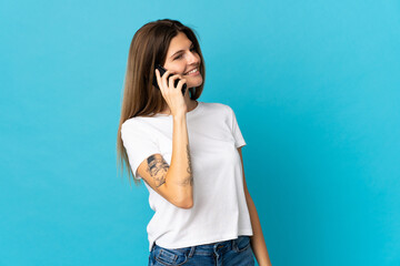 Young slovak woman isolated on blue background keeping a conversation with the mobile phone with someone