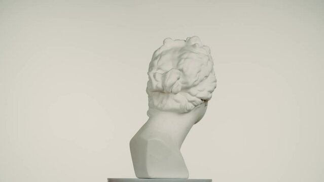 Closeup shot. Ancient marble bust statue of roman era woman spinning round on a platform. Isolated on white background.