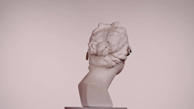 Closeup shot. Ancient marble bust statue of roman era woman in 3d glasses spinning round on a platform. Isolated on pink background.