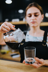 Barista girl prepares coffee through a cone filter - classic drip brewing method