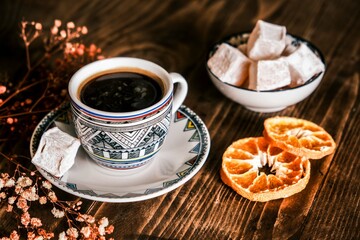 Turkish Coffee with traditional porcelain cup on a wooden table. Coffee presentation with Turkish delight and dried orange slices