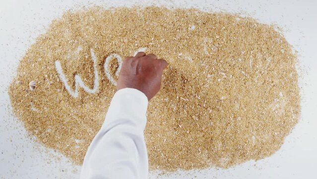 An Indian man's Hand Writes On Beach Sand words We are open