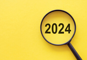 Focused on business concept. Magnifier glass with word numbers 2024 on yellow table. Business...