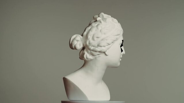Closeup shot. Ancient marble bust statue of roman era woman with sticking tape on her eyes spinning on a platform. Isolated on grey background.