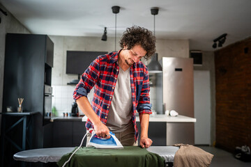one man ironing clothes at home hold iron household chores concept