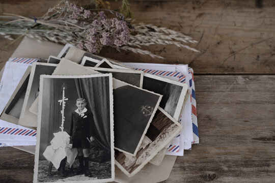 black old family photos, stack of old family vintage photographs of 50s, 40s, letters envelopes on retro wooden table, concept of genealogy, memory of ancestors, family tree, home archive documents