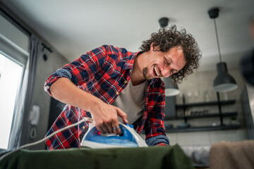 one man ironing clothes at home hold iron household chores concept