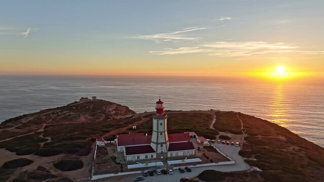 Aerial drone view of lighthouse on Cabo Espichel cape Espichel on Atlantic ocean at sunset. Sesimbra, Portugal. Orbit parallax shot