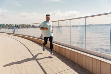 Athlete runner full-length workout in sportswear. Uses a fitness watch and an app.   A sporty man running a lot in running shoes.  Man running in the city fresh air.