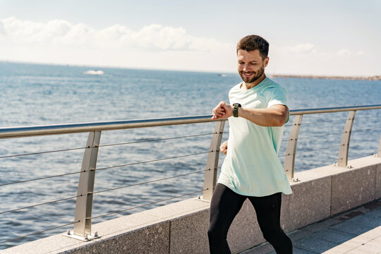 A coach with glasses does a running exercise every day, a healthy lifestyle. A sporty person Uses a fitness watch and a running app. A man training fitness in a comfortable T-shirt.