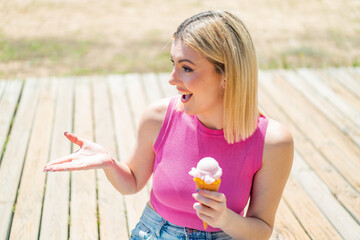 Young pretty blonde woman with a cornet ice cream at outdoors with surprise facial expression