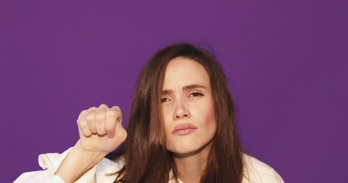 Attractive brunette woman in jeans white jacket isolated on purple background. Curious, suspicious, woman look at camera, knocking, breathes steam on the glass, wipes.