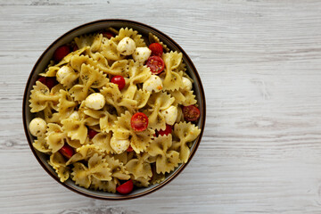 Homemade Pesto Pasta with Tomatoes and Mozzarella in a Bowl, top view. Flat lay, overhead, from above. Copy space.