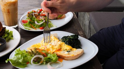Man enjoying healthy full nutrition in restaurant. Close-up menu of full nutrition in restaurant poached eggs, salad, healthy burger, avocado toast. Concept visit restaurant to have full nutrition.