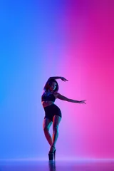 Deurstickers Beautiful female dancer wearing black and high heels while performing pole dance tricks in gradient neon light © Lustre