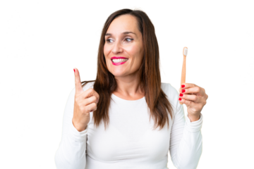 Middle age woman brushing teeth over isolated chroma key background intending to realizes the solution while lifting a finger up