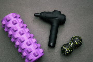 Rehabilitation sports medicine concept. Percussion Massage Gun, Resistance band, Myofascial foam rollers on the yoga mat.