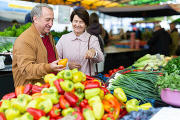 Elderly man and a woman buy pepper at an open-air market