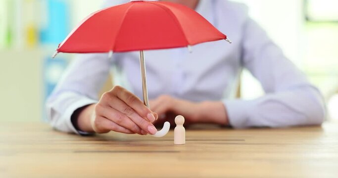 Hand holds red umbrella with human figurine. Insurance coverage and protection of people rights