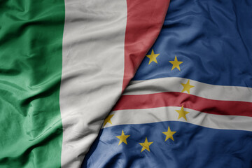 big waving national colorful flag of italy and national flag of cape verde .