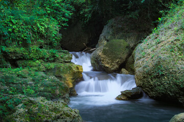 Tropical landscape. Beautiful hidden waterfall in rainforest. Adventure and travel concept. Nature background. Slow shutter speed, motion photography. Pangandaran, Indonesia