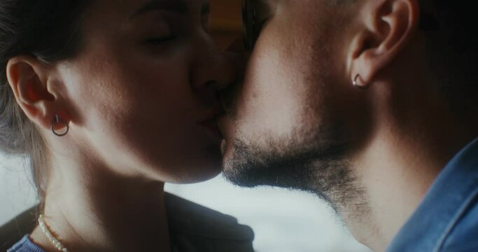 Young happy man and woman kissing sitting on a bed in a van. A romantic trip. Close-up of faces
