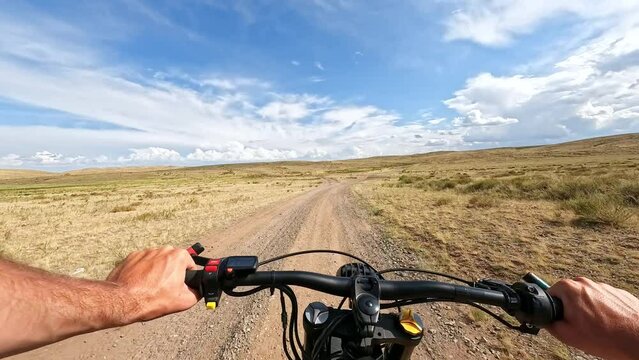 POV: Electric Bike Riding through the Hilly Steppe with a Radio Mast in the distance at Partly-Cloudy Day. 60 fps, H.264, 8bit, chroma subsamlping 4:4:4