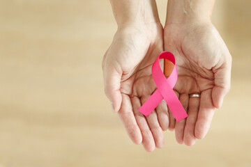 Adult Woman hand holding Pink Ribbon, October Breast Cancer Awareness month with copy space