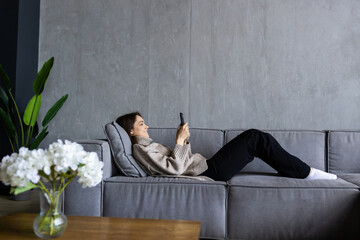 Beautiful woman sitting on a white sofa holding a phone.