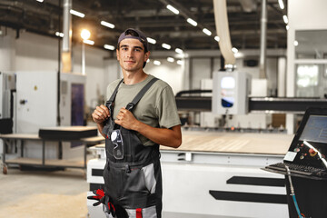 Portrait of young male carpenter standing in the wood workshop