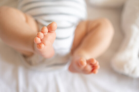 The tiny foot of a newborn baby. Soft feet of a new born in a white blanket. Close up of toes and feet of a newborn. Macro photography.
