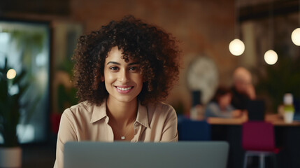 Close Up Portrait of a Happy Middle Eastern Manager Sitting at a Desk in Creative Office. Young Stylish Female with Curly Hair Using Laptop Computer in Marketing Agency - obrazy, fototapety, plakaty