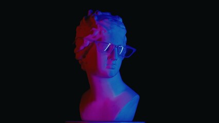 Closeup shot. Ancient marble bust statue of roman era woman in glasses in neon lights. Isolated on black background.