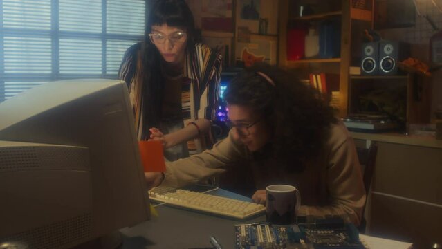 Young man and woman working together in retro garage office saving data onto floppy disk, 90s aestheticsYoung man and woman working together in retro garage office saving data onto floppy disk, 90s ae