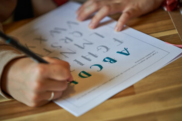Woman outlining letters with marker on paper sheet