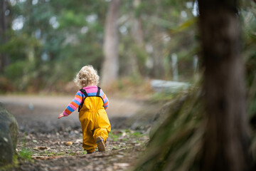 baby walking in a park in yellow overalls
