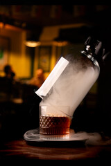 drink smoker from a glass of smoked cognac with smoke on blurred pub wooden table