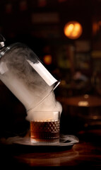 drink smoker from a glass of smoked whiskey with smoke on blurred pub wooden table