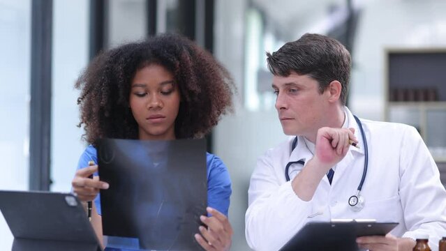 Two doctors looking at human's x-ray and sitting in hospital, medicine and healthcare concept.