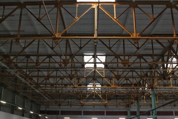 Interior of empty factory. Modern design of warehouse industrial building. Urban loft style on workshop space with metal constructions and pipes under the beton ceiling. Steel roof frame