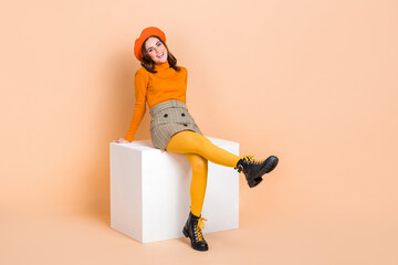 Full body photo of adorable satisfied lady sit podium toothy smile isolated on beige color...
