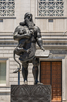San Francisco, CA, USA - July 12, 2023: Closeup, Statue of historic Ashurbanipal Assyrian king or Enkidu holding a wriggling lion and a tablet, at south facade of Asian Art Museum.