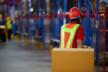 back view worker pushing cart with corrugated boxes in the warehouse storage