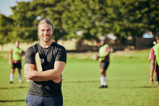 Portrait, fitness and a rugby coach on a field with his team training or getting ready for match competition. Exercise, sports and strategy with a happy male trainer on grass for practice workout