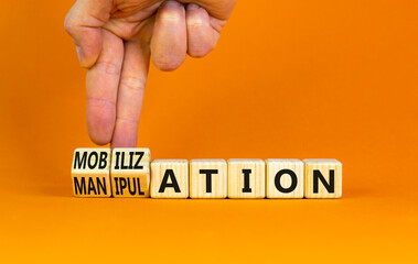 Mobilization or manipulation symbol. Concept words Mobilization Manipulation on wooden cubes. Beautiful orange background. Psychologist hand. Psychology mobilization manipulation concept. Copy space.