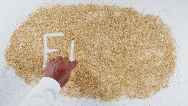 An Indian man's Hand Writes On Beach Sand words Eleven
