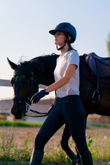 A helmeted rider leads her beautiful black horse by the harness in the riding arena during a...