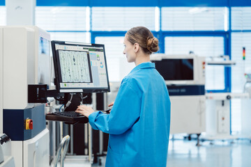 Manufacturing worker checking data on performance of assembly line on screen - 641405366