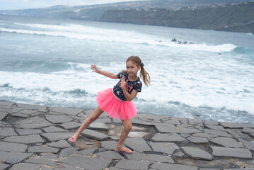 A little girl with ponytails runs along the sea embankment in Georgia